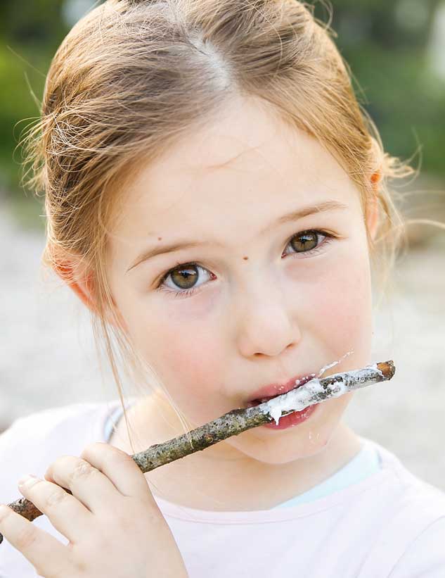 Cute girl in a witch costume sitting at a campsite, holding a pumkin